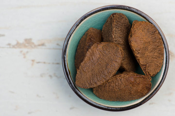 Brazil nuts in a turquoise bowl on a white shabby background