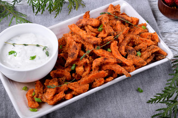 Spicy sweet potato fried sticks and yogurt sauce served on white ceramic plate