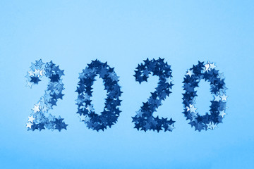The numbers 2020 are laid out from stars on a bright blue background. Winter holidays and christmas overlay. Top view, flat lay. lolr of the year 2020.