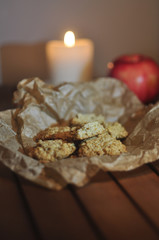 Oatmeal cookies on parchment paper on a background of apple and candles
