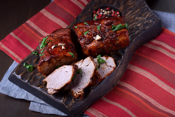 Wine glazed pork tenderloin cut into slices served on the wooden board