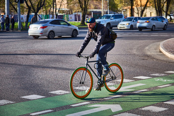 Guy is cycling around the city. Intersection on a cycle path. Eco-friendly mode of transport