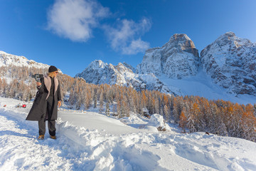 Fototapeta na wymiar Blonde woman take photo with phone of awesome snowy landscape, Mount Pelmo, Dolomites, Italy. Concept: technology, happy people surrounded by nature, happy people on vacation