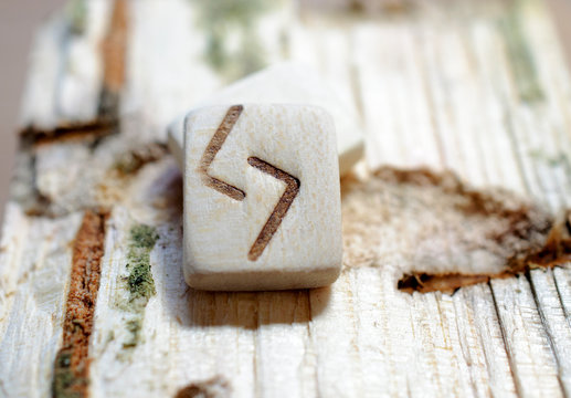 Wooden rune Jera close-up on a wooden background. Soft focus