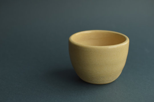 Blurred handmade ivory color ceramic bowl at pastel gray background. Minimalist lifestyle. Calm mood.