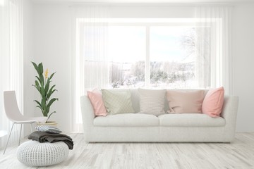 Fototapeta premium Stylish room in white color with sofa and winter landscape in window. Scandinavian interior design. 3D illustration