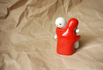 Two symbolic bodies hugging on the background of natural paper with free copy space