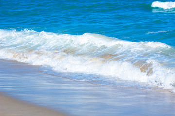 Beautiful, clear blue of the sea. Emerald Ocean, white wave foam on golden sand