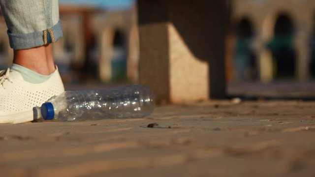 A person drops empty plastic bottle on the street . Environmental pollution concept