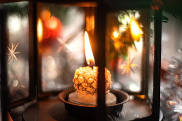 Candle in a Candle holder close-up with a candle on the background of spruce branches, red Christmas balls and silver tinsel. Christmas candle. Christmas toys, snow, Merry Christmas.