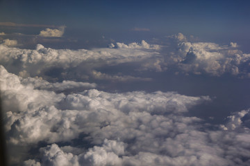 Top view of clouds from the porthole of an airplane on a sunny day