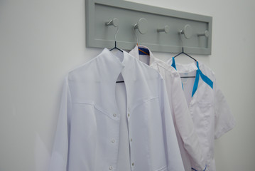 A white medical gown hangs on a hanger. White background. Concept.