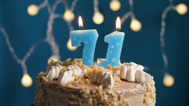 Birthday cake with 71 number candle on blue backgraund. Candles blow out. Slow motion and close-up view