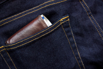 Wallet and usd banknote showing in back pocket of jeans. Selective focus on the edge of the wallet.