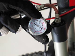 Close up. Man serving a bicycle, checking a air pressure in the pneumatic absorber.