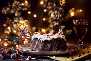 Traditional homemade Christmas chocolate cake with icing on the background of festive lights in bokeh and holiday decoration Food photo concept. Rustic style