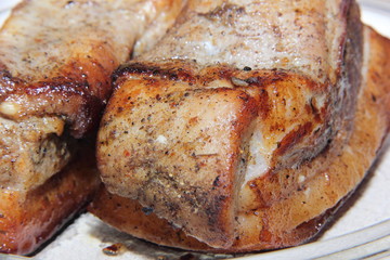 Baked piece of pork meat on aluminum foil, the process of cooking meat dishes in the oven.