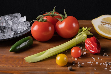 Fresh organic tomato juice decorated with raw tomatoes, leaves on a dark rustic wooden background. Healthy diet nutrition concept. 