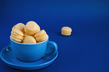 On a blue classic background, a blue cup with macaron horizontal view, soft focus, closeup