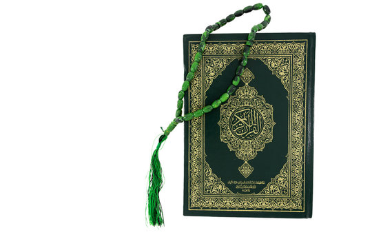 Quran and green rosary beads isolated on white background. Arabic word translation : The Holy Al Quran (holy book of Muslims). Islamic concept with copy space.