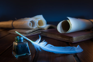 Quill pen and rolled papyrus sheets on a wooden table with old books