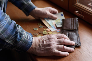 The hands of an old man and counting money, euros. The concept of poverty, low income, austerity in...