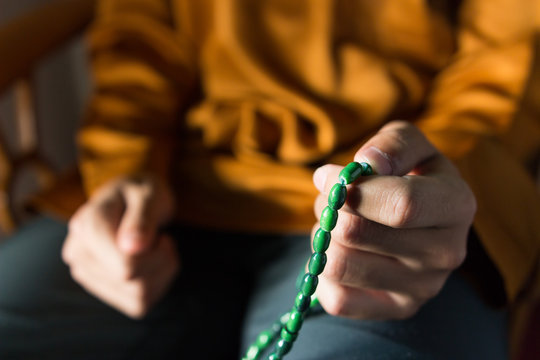 Islamic concept of a muslim guy holding Islamic rosary. Selective focus on rosary with small depth of field, image may contain soft focus.