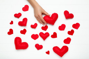 Fabric heart in female hand on white wooden table