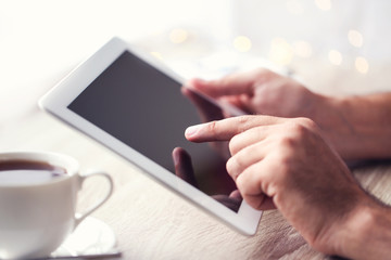 Male hands holding and using tablet computer