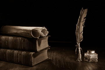 Quill pen and rolled papyrus sheets on a wooden table with old books, sepia effect