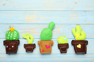 Different soft toy of cactuses on blue wooden table