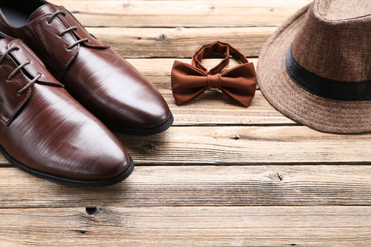 Male leather shoes with hat and bow tie on brown background