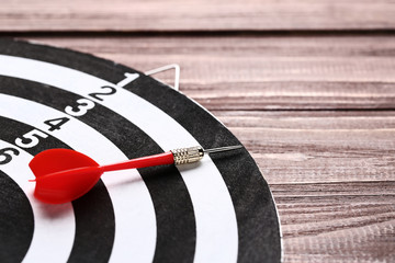 Dartboard with darts on brown wooden table