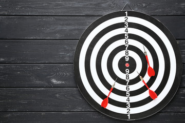 Dartboard with darts on black wooden table