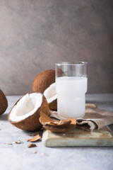 Cracked fresh coconut, milk  and slice nut on concrete background, space for text Food ingredients, healthy lifestyle, paradise concept