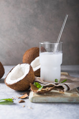 Cracked fresh coconut, milk  and slice nut on concrete background, space for text Food ingredients, healthy lifestyle, paradise concept
