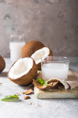 Cracked fresh coconut, milk  and slice nut on concrete background, space for text Food ingredients, healthy lifestyle, paradise concept