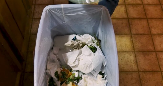 Man throwing away uneaten leftover food into a trash can