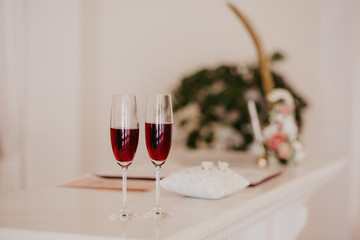 Big golden feather and glasses with rose champagne. Folder with documents on signing marriage certificate, golden rings closeup. Folder with documents on signing marriage certificate
