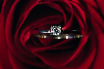 Top view of a red rose and a golden ring with a pebble