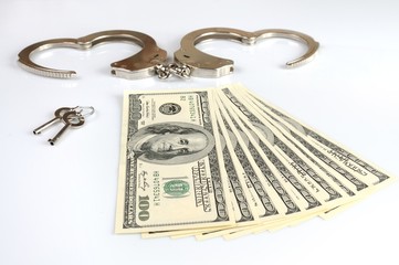 Open metal handcuffs, keys and stack of american dollars cash