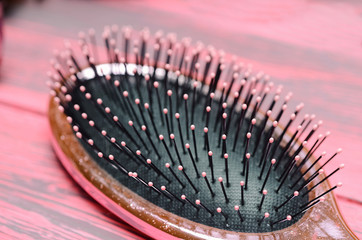 pink hairbrush close up on a pink wooden background