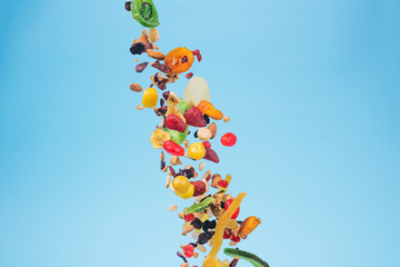 Dried and candied fruits and nuts flying on blue background. Stock photo of healty and nutrient...