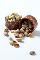 Pistachio and Cashew Nuts in clay pots on white background