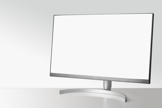 Modern monitor on white table and light background.