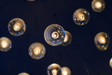 lighting balls on the chandelier in the lamplight, light bulbs hanging from the ceiling, lamps on the dark background, selective focus, horizontal