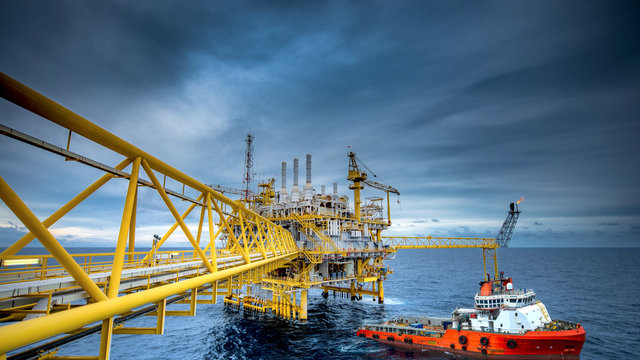 The Shipping Box Is Loaded From An Offshore Oil Rig To The Supply Vessel At Sunset.