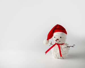 Smiling snowman in Santa hat handmade crocheted white thread. On white background.