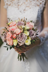 Bouquet of flowers in the hands of the bride in a wedding openwork whi
