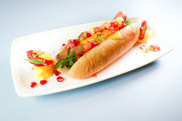Hot dog with real Bavarian sausage and cheddar cheese. White plate. Gray background. Restaurant